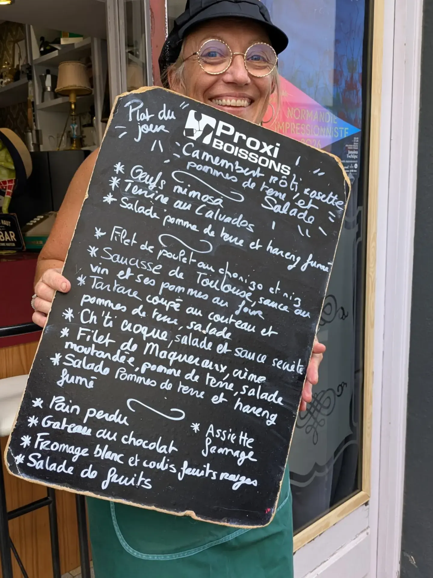 Clara, gérante de La Belle Époque, souriante devant le restaurant avec l’ardoise du jour